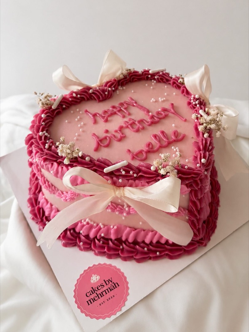 A hot pink heart-shaped buttercream cake finished with a ribbon bow